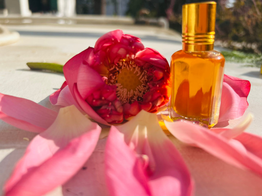 Pink lotus flower with a bottle of orange liquid on a blurred outdoor background